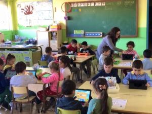 Niños y niñas en un aula usan apps de educación