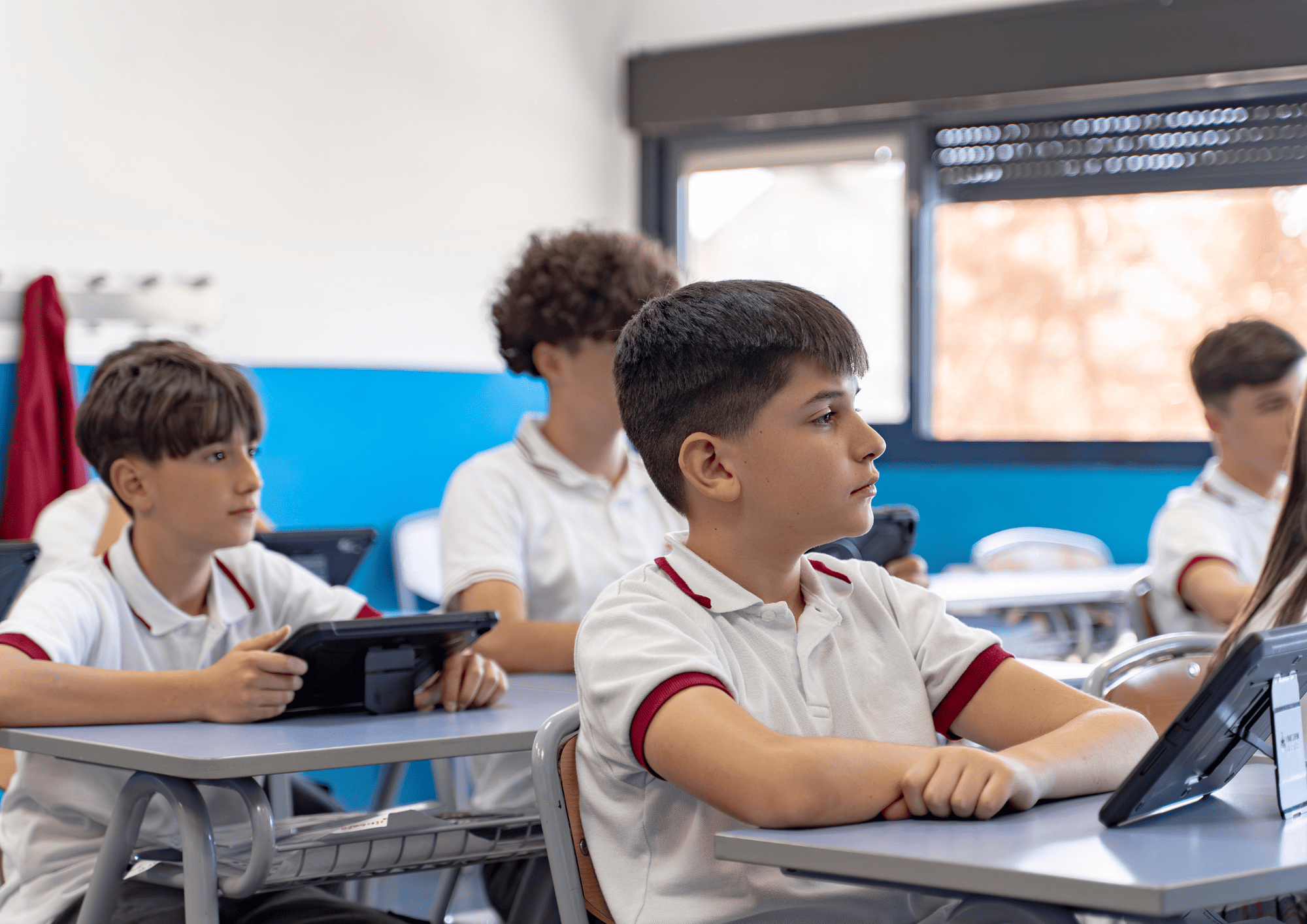 Primary school pupils in uniform working on tablets in class with inclusive educational apps